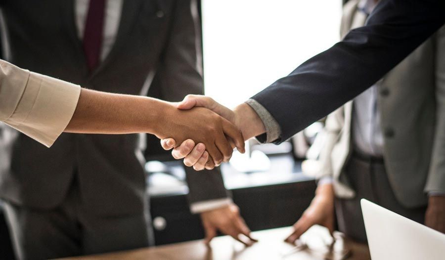 A woman is shaking hands with a man in a suit and tie.