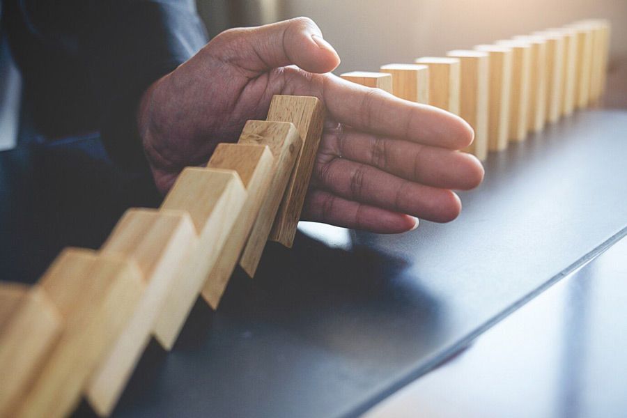 A person is stopping a row of wooden dominoes from falling.