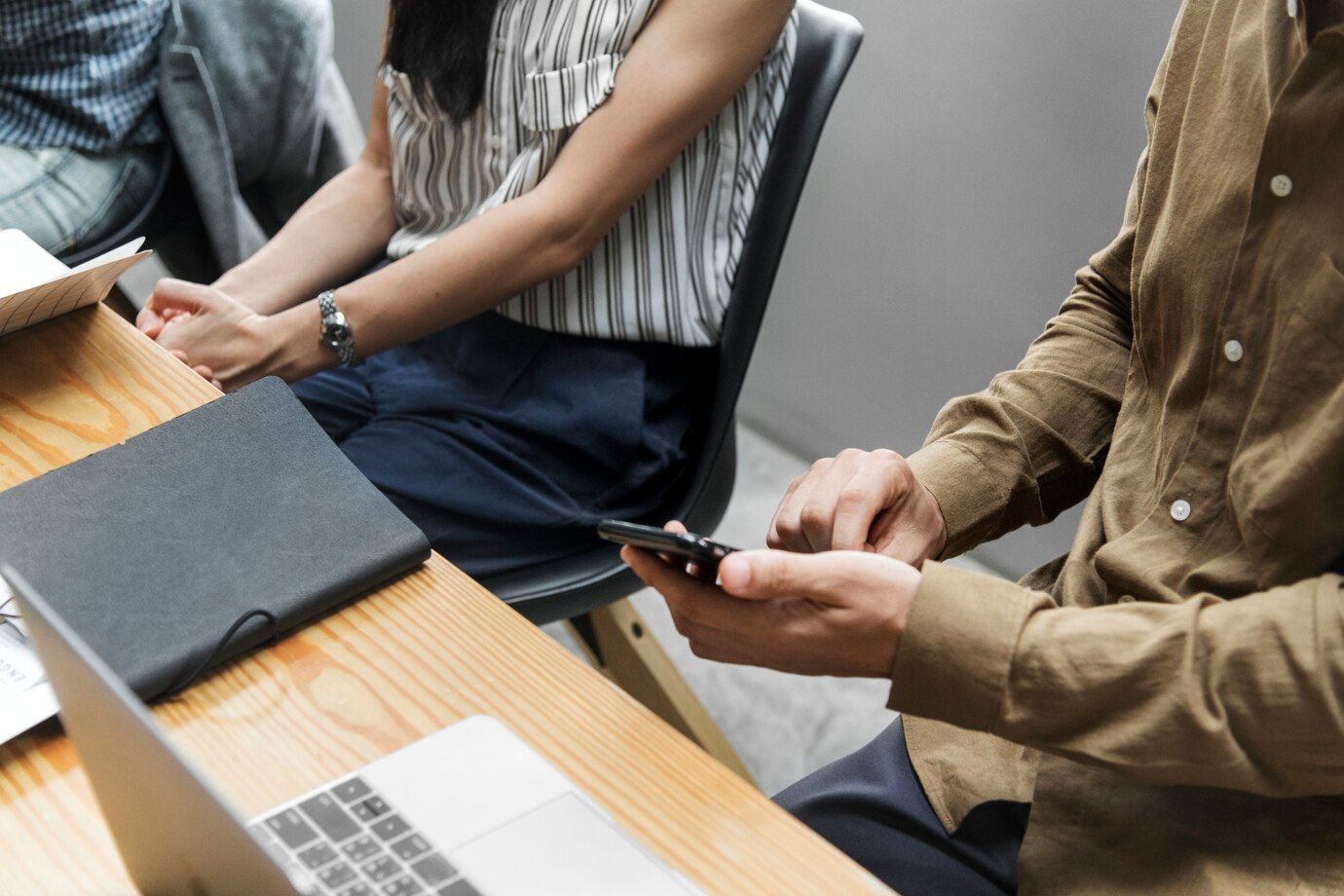 A man and a woman are sitting at a table looking at a cell phone.