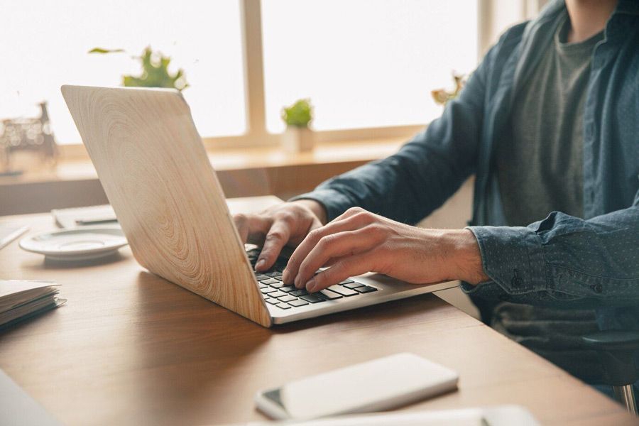 A man is typing on a laptop computer at a desk.