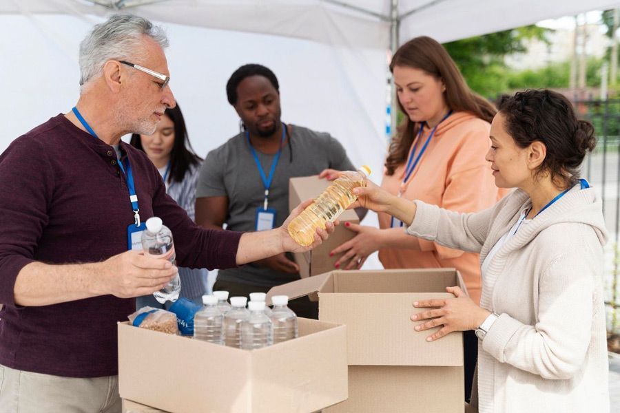 A group of people are standing around a box of food.