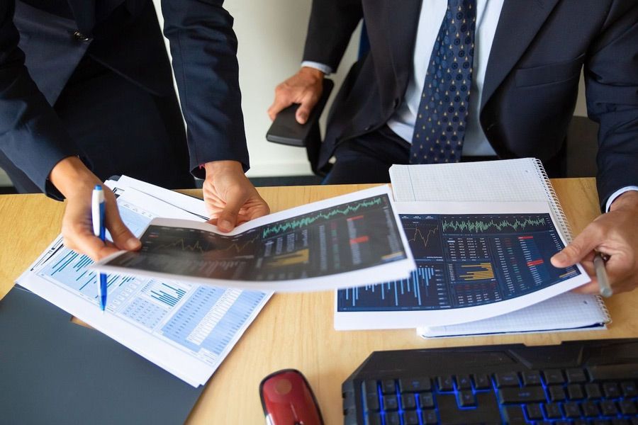 A man and a woman are sitting at a desk looking at papers.