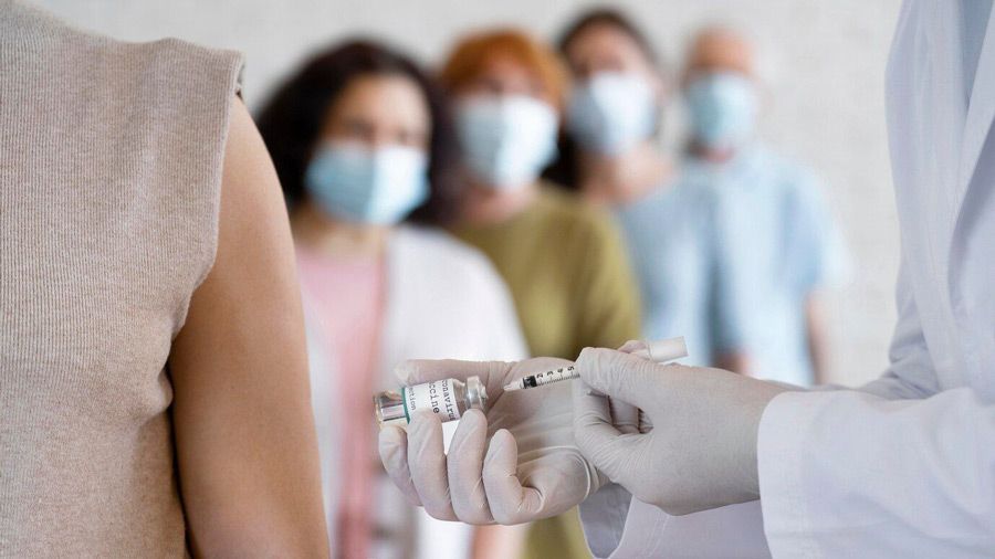 A group of people wearing masks are getting a vaccine from a doctor.