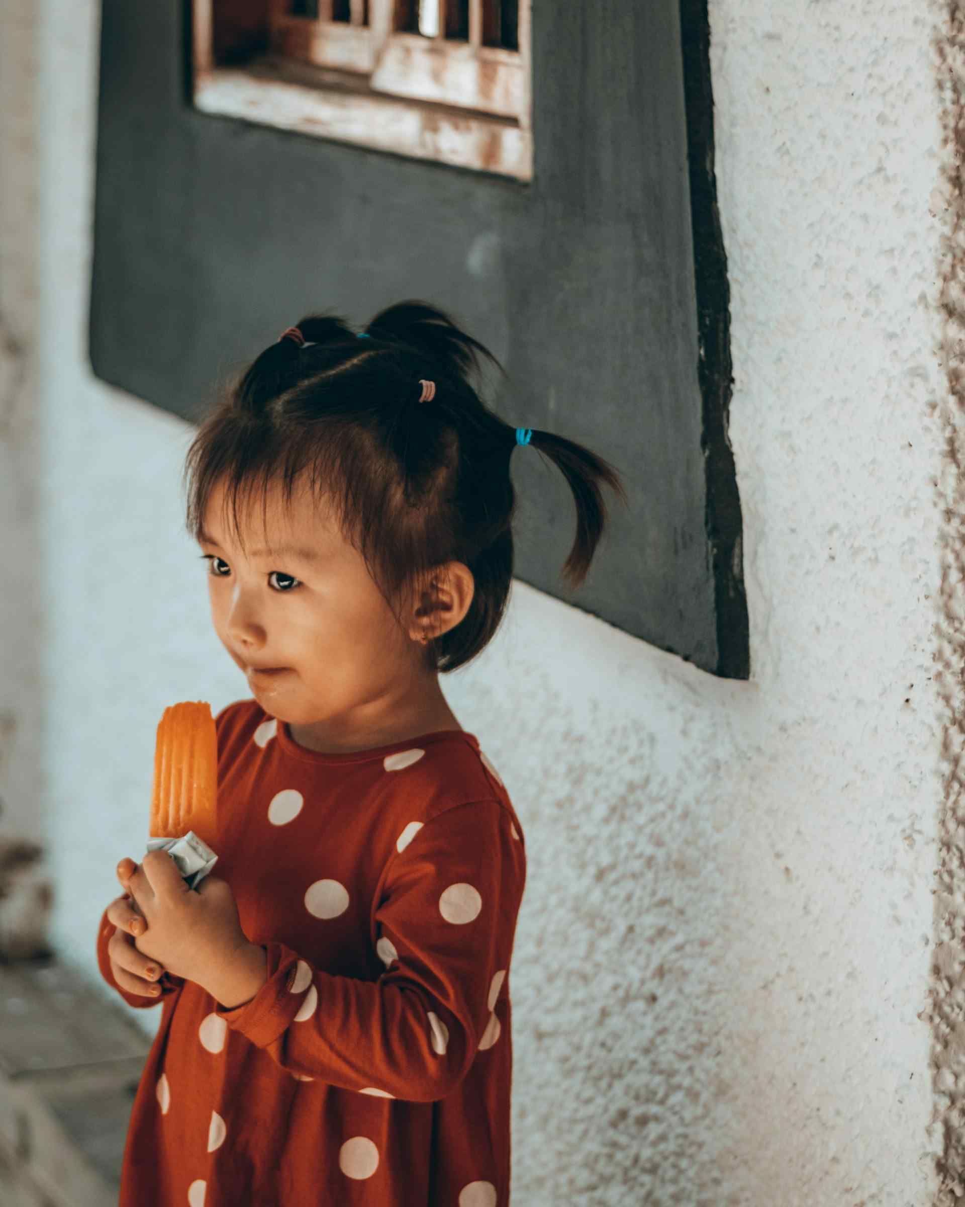 A Young Girl With An Orange Popsicle