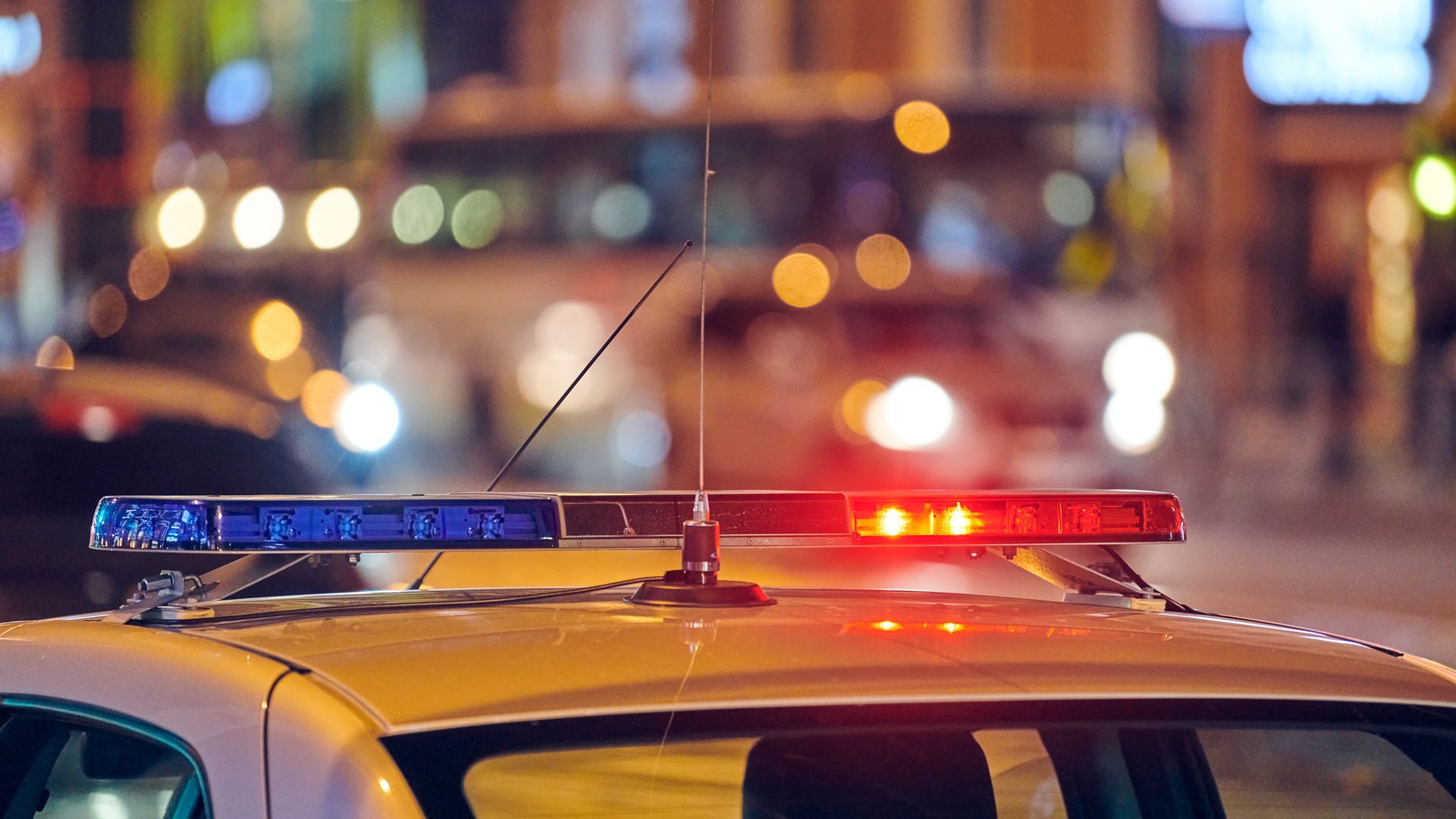 Police car with flashing red and blue lights at night.
