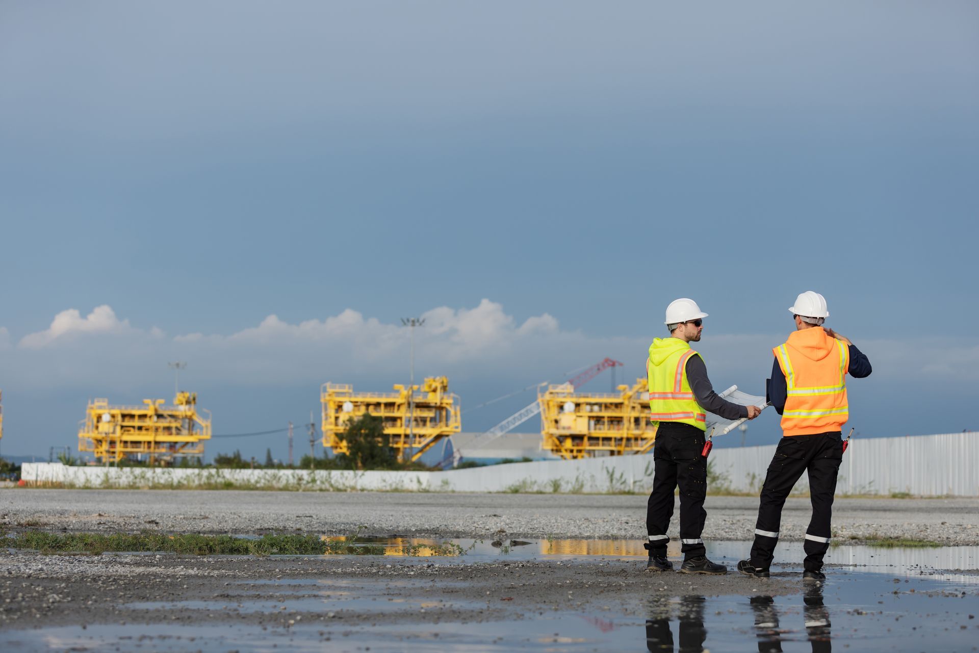Two construction workers, wearing hard hats and safety vests