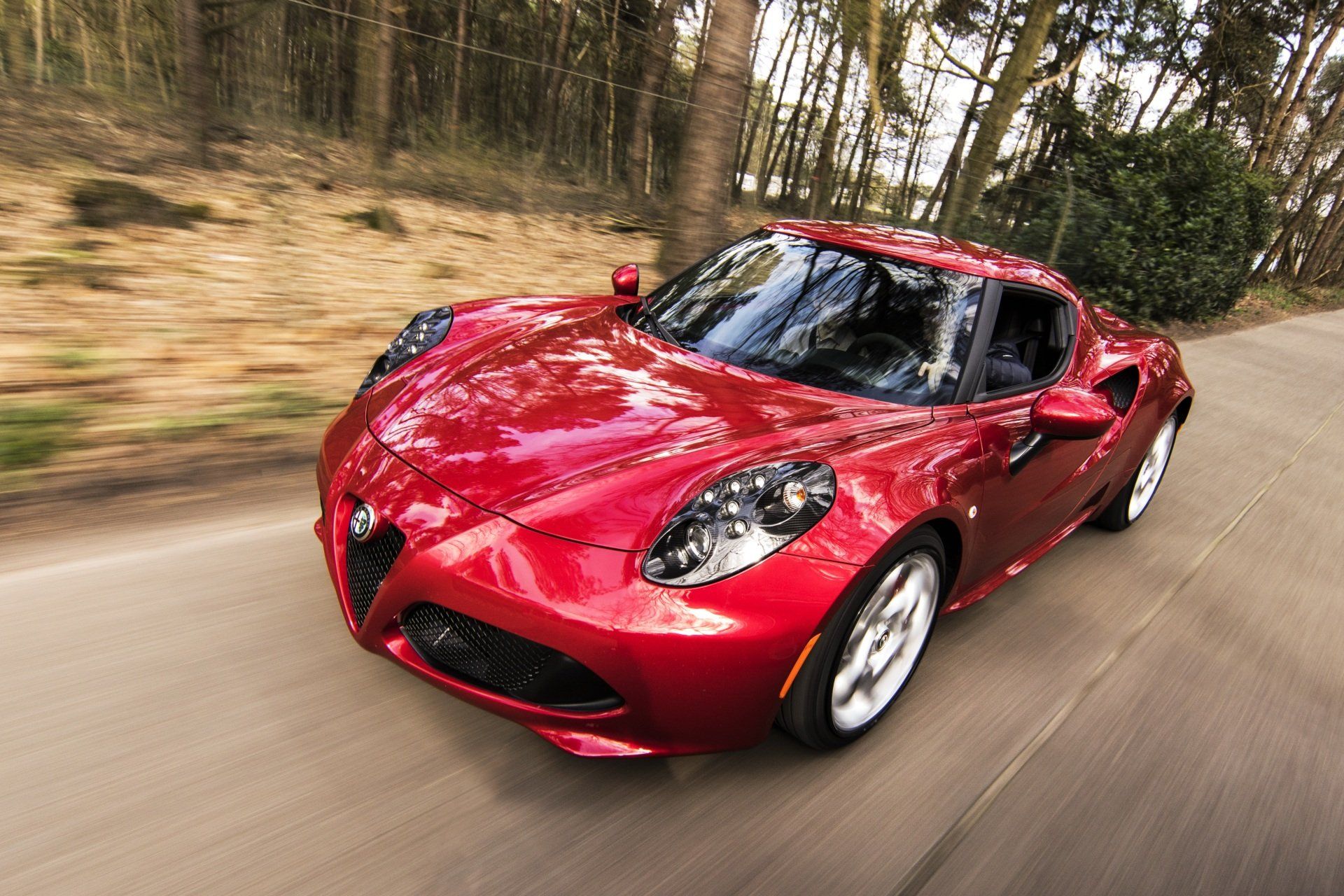 A red sports car is driving down a road