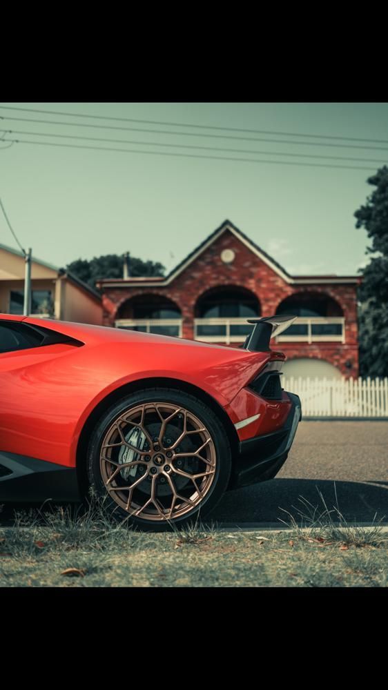A red sports car is parked in front of a brick building.