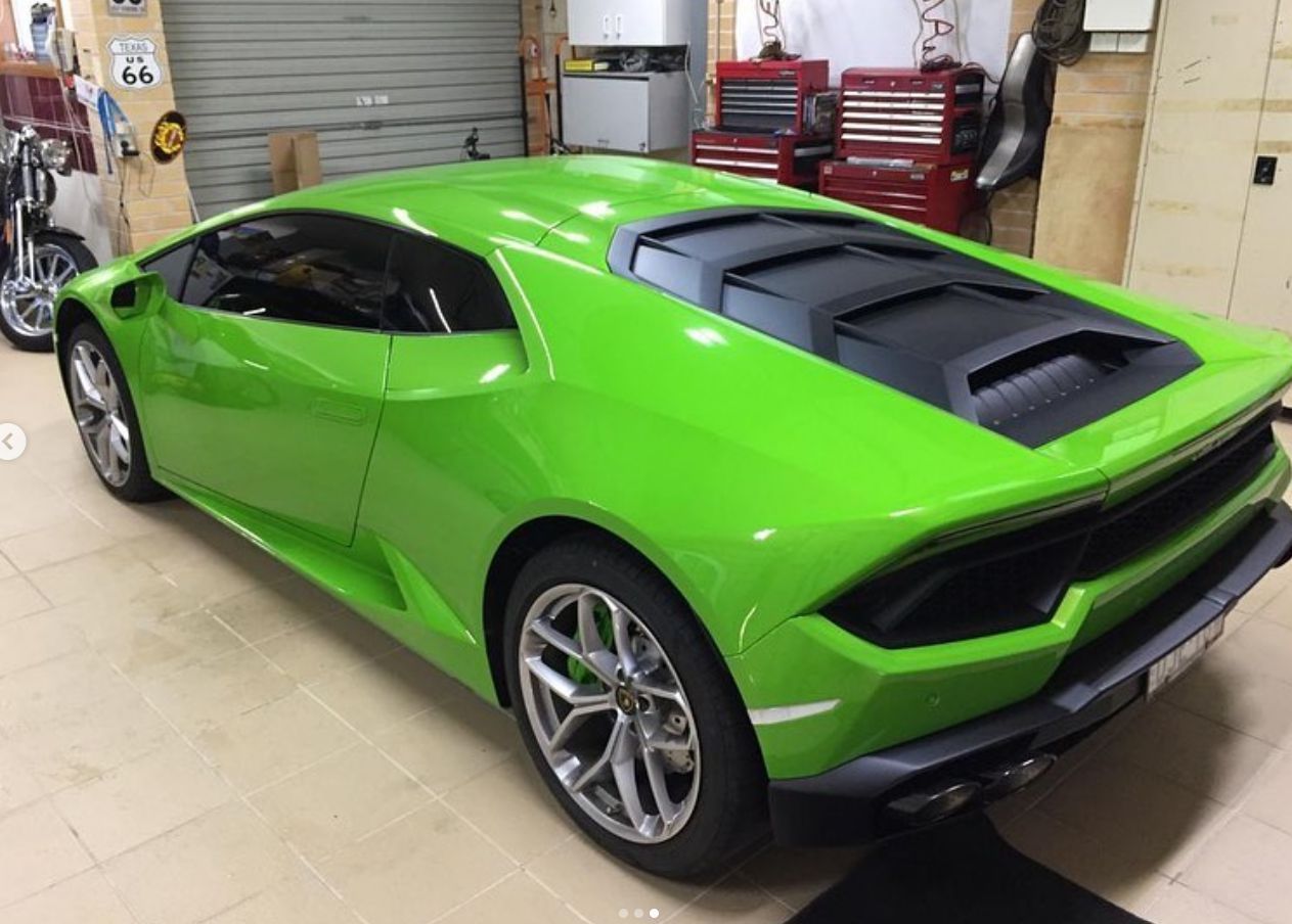 A green sports car is parked in a garage