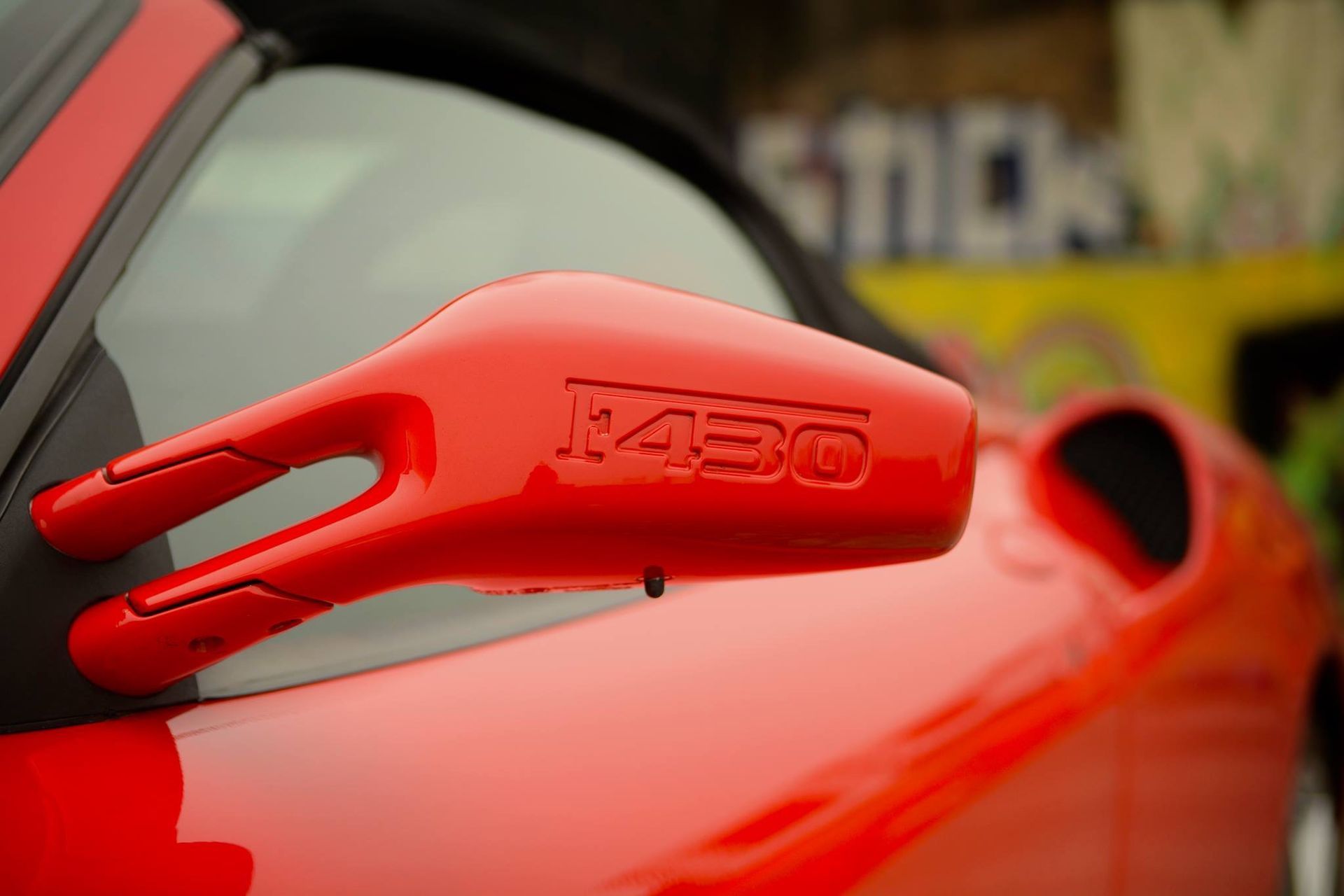 A red car with the word x450 on the side mirror