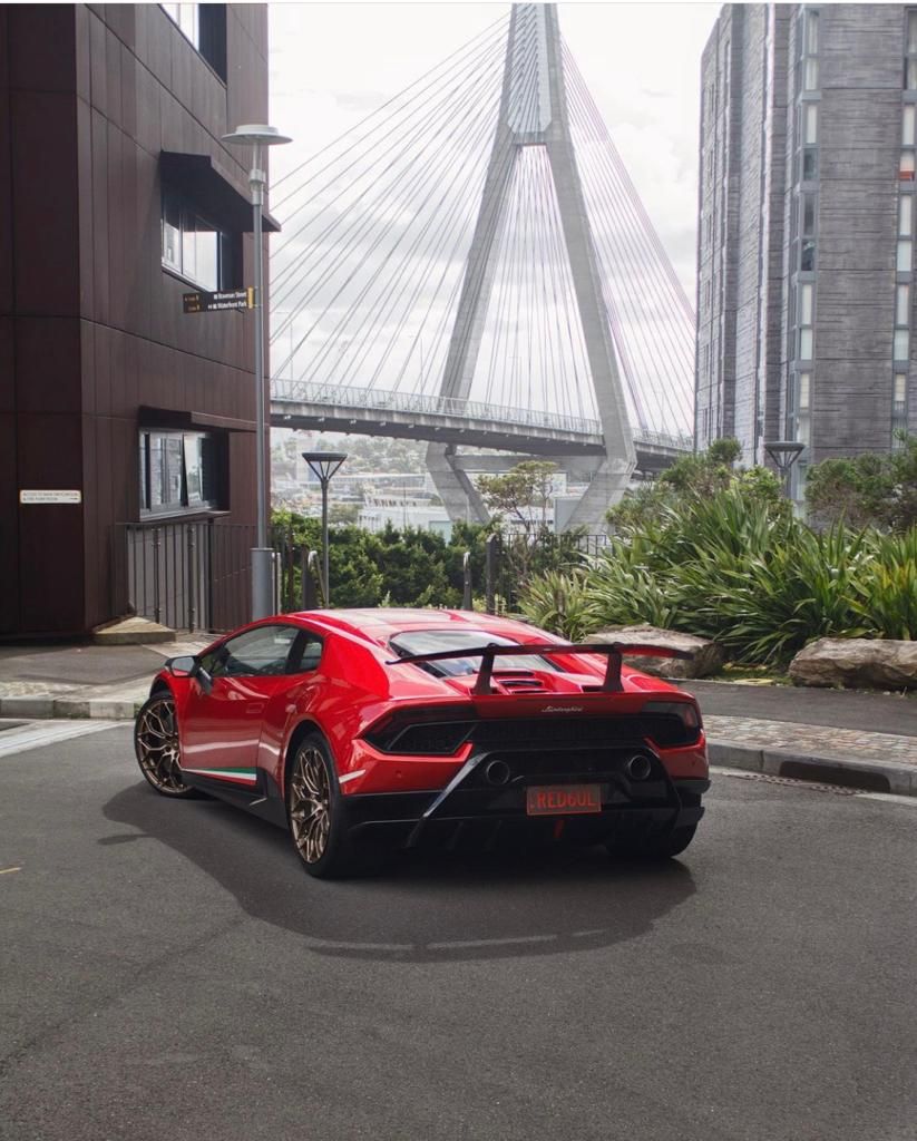 A red sports car is parked in front of a bridge