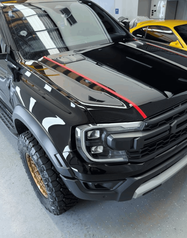 A black truck with a red stripe on the hood with ceramic coating