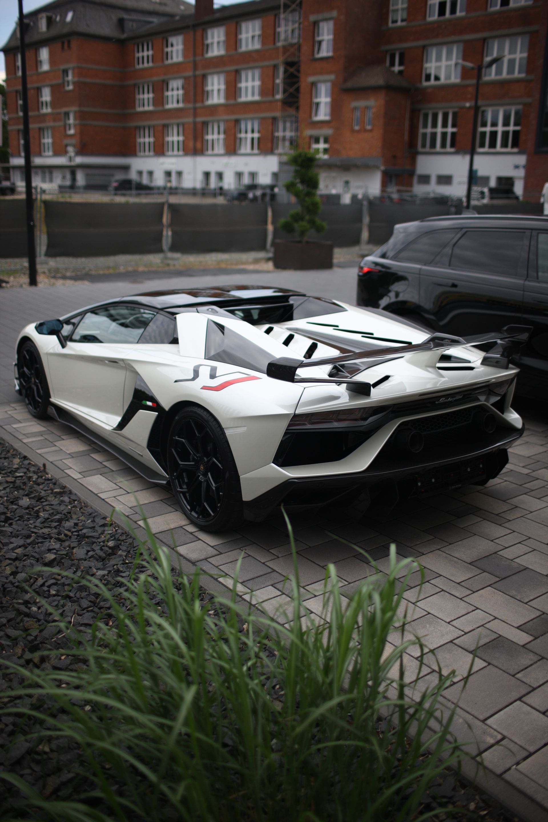 A white lamborghini aventador is parked on the side of the road