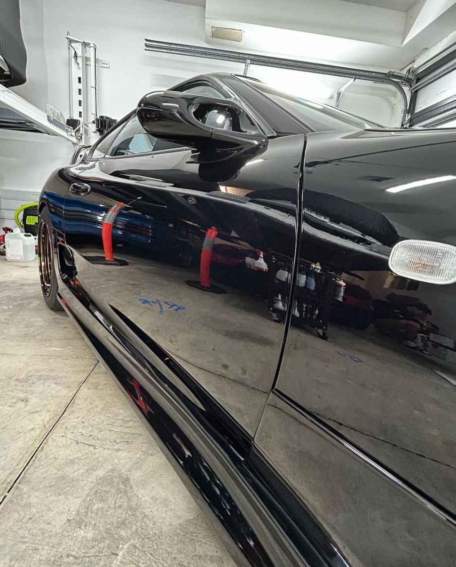 A black car is parked in a garage next to a blue car.