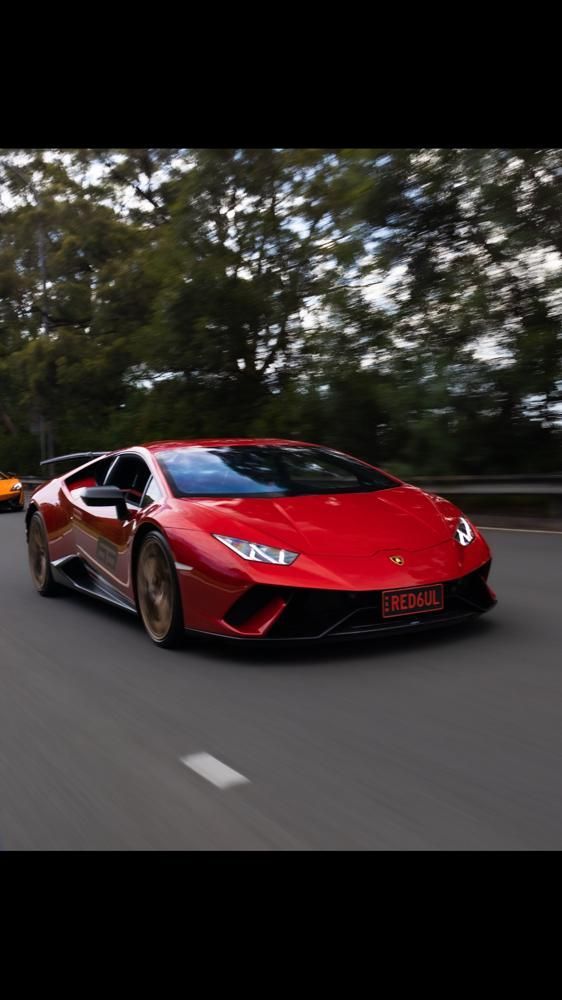 A red lamborghini huracan is driving down a road.