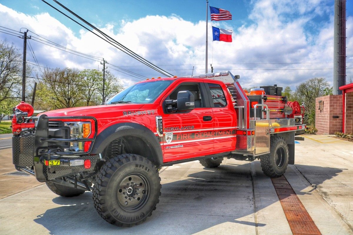 A red brush fire truck is parked in front of a fire station.