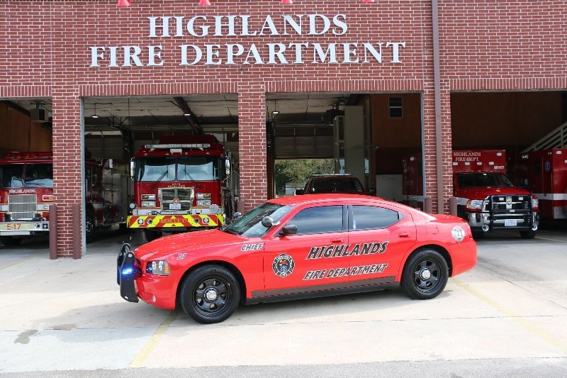 A red Highlands fire department car is parked in front of a fire station.