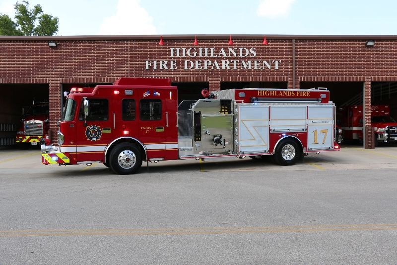 A red fire truck is parked in front of a Highlands fire department fire station