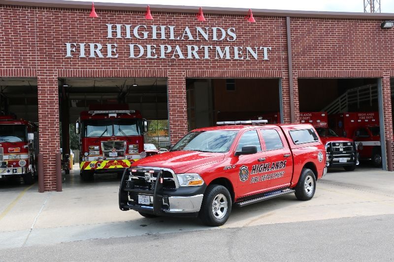 A red fire command truck is parked in front of a Highlands fire department fire station