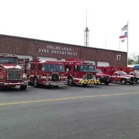 A row of fire trucks parked in front of a Highlands Fire department building.