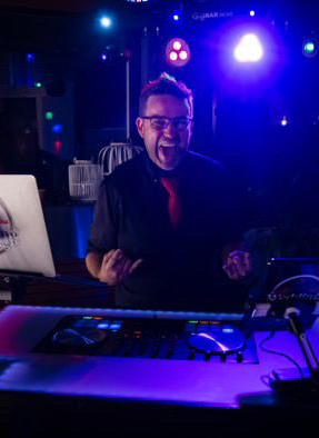 Jay behind the DJ decks, crowd energy in the background