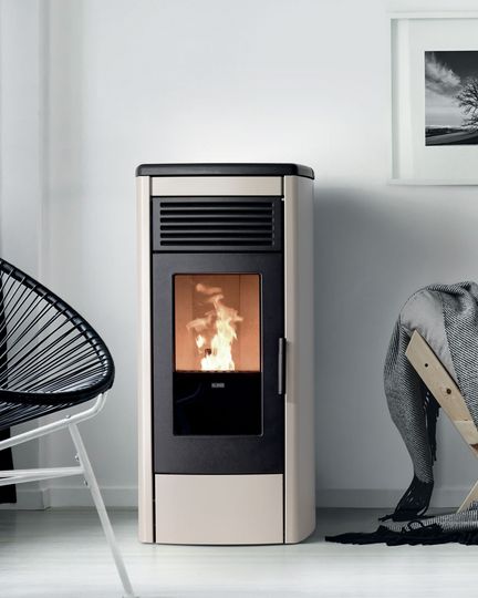 Caminetto moderno color beige con fuoco acceso in un soggiorno minimalista, affiancato da una poltrona e una scultura.