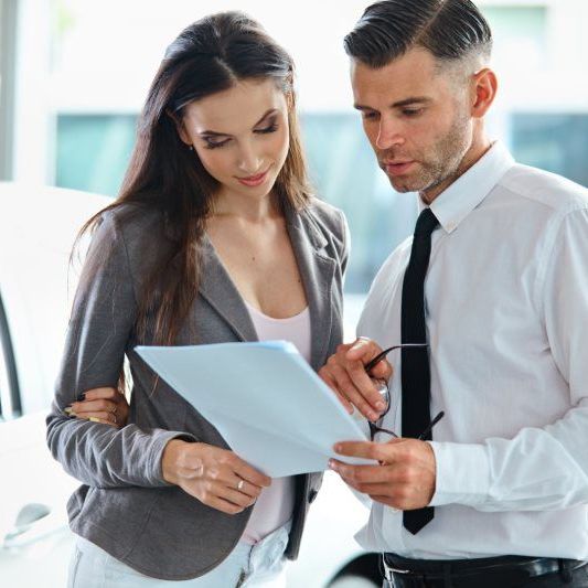 Woman and man reviewing documents at car dealership.