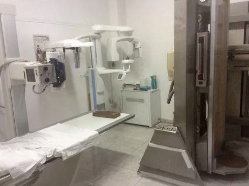 Sala di radiologia ospedaliera con apparecchio a raggi X e lettino per esami.