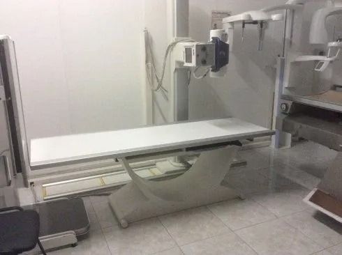 Tavolo radiografico in una sala di radiologia ospedaliera con apparecchiatura di imaging e monitor soprastante