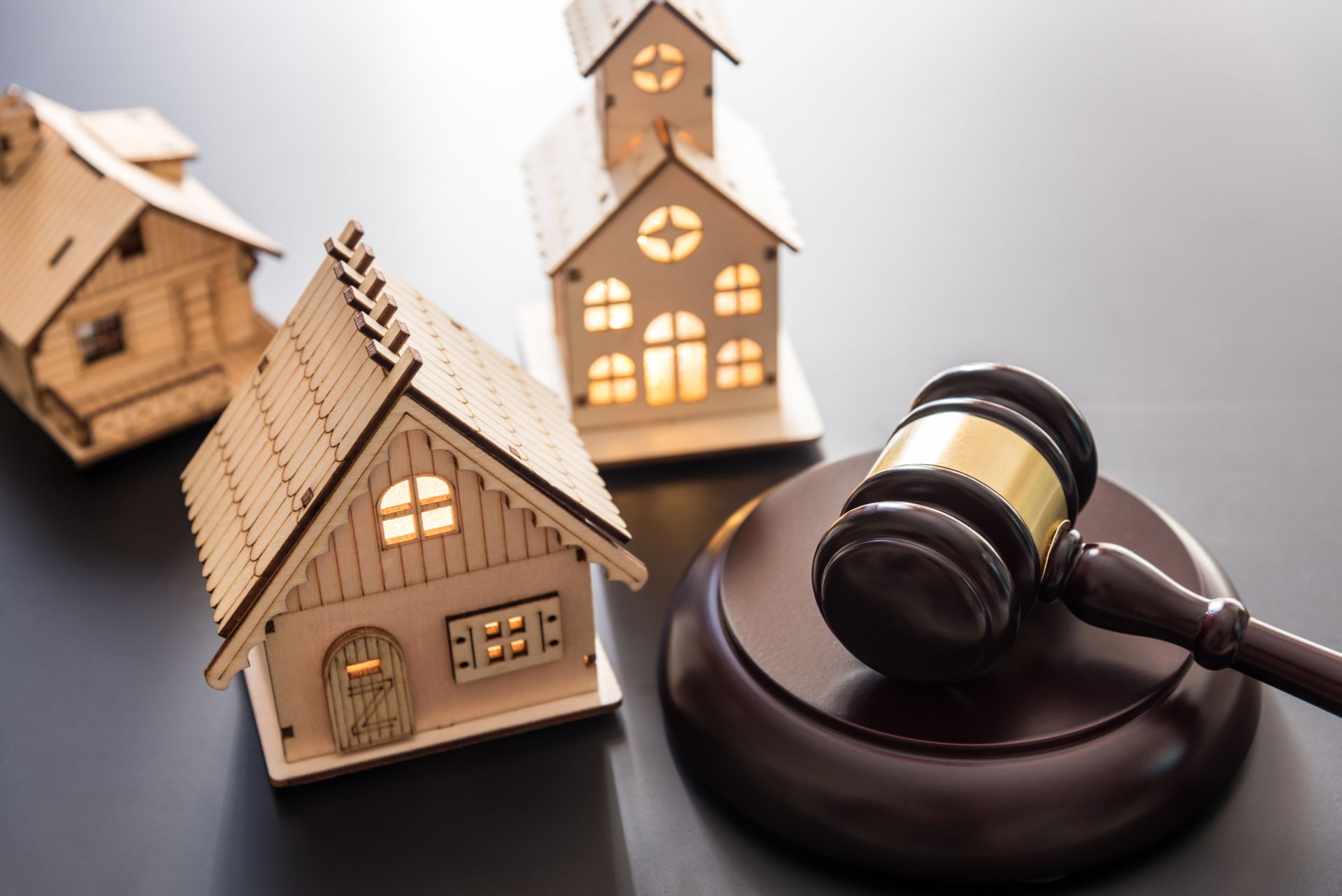 Miniature houses with a gavel on a dark surface, symbolizing real estate auction.