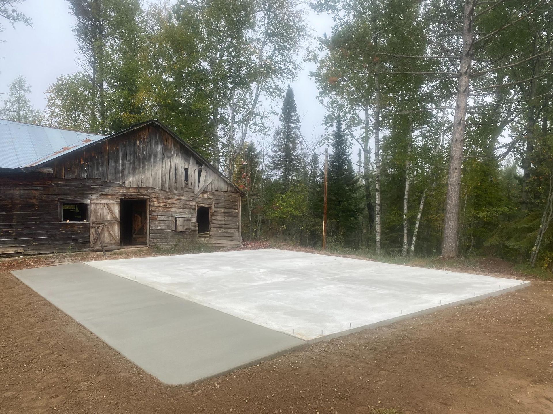 A large concrete slab is sitting in front of a log cabin in the woods.