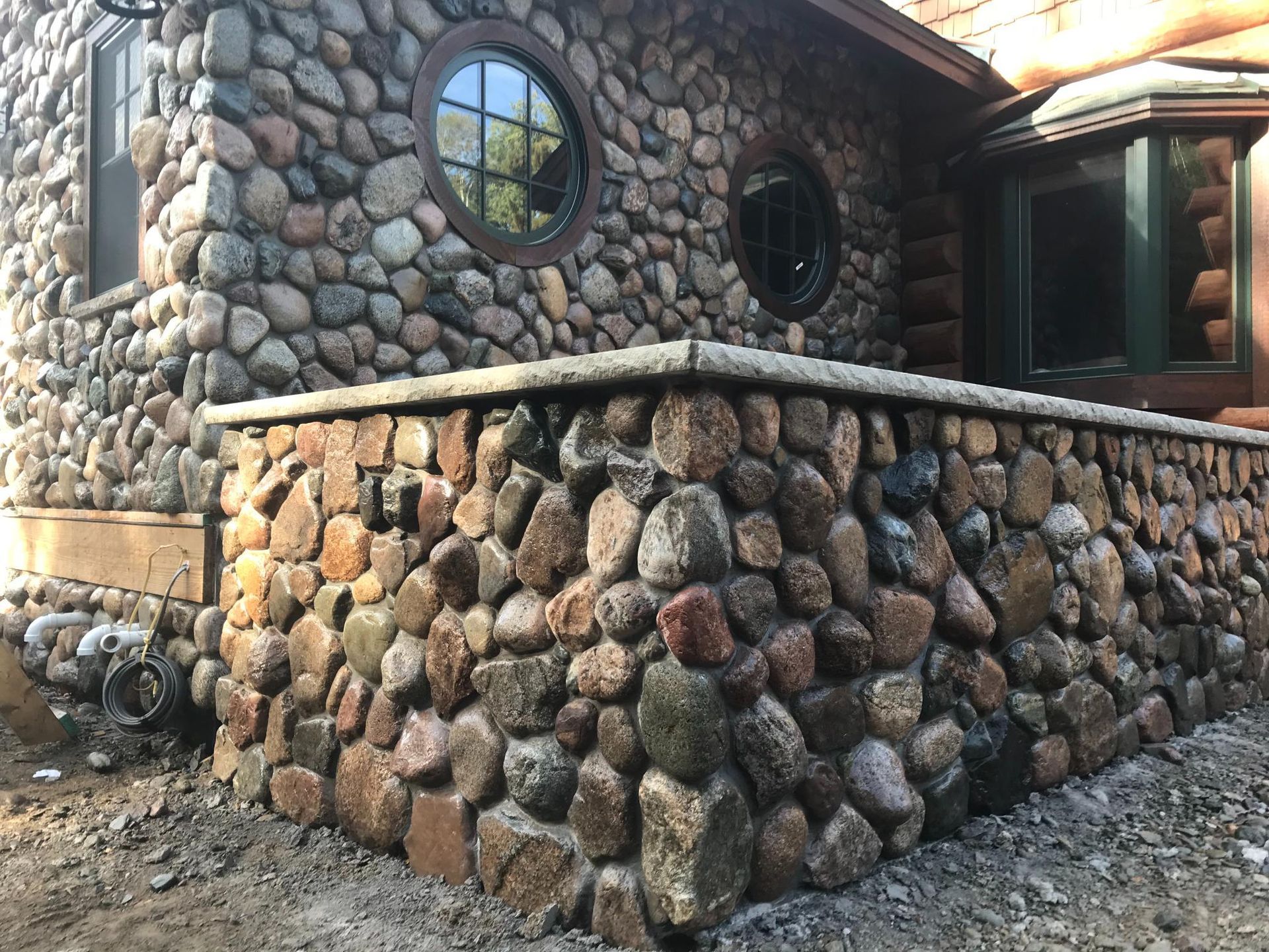 A house with a stone wall and a round window.