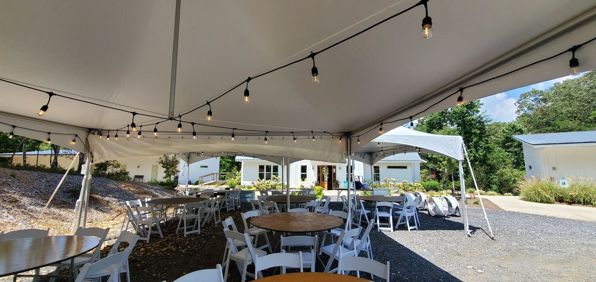 A large white tent with tables and chairs underneath it.