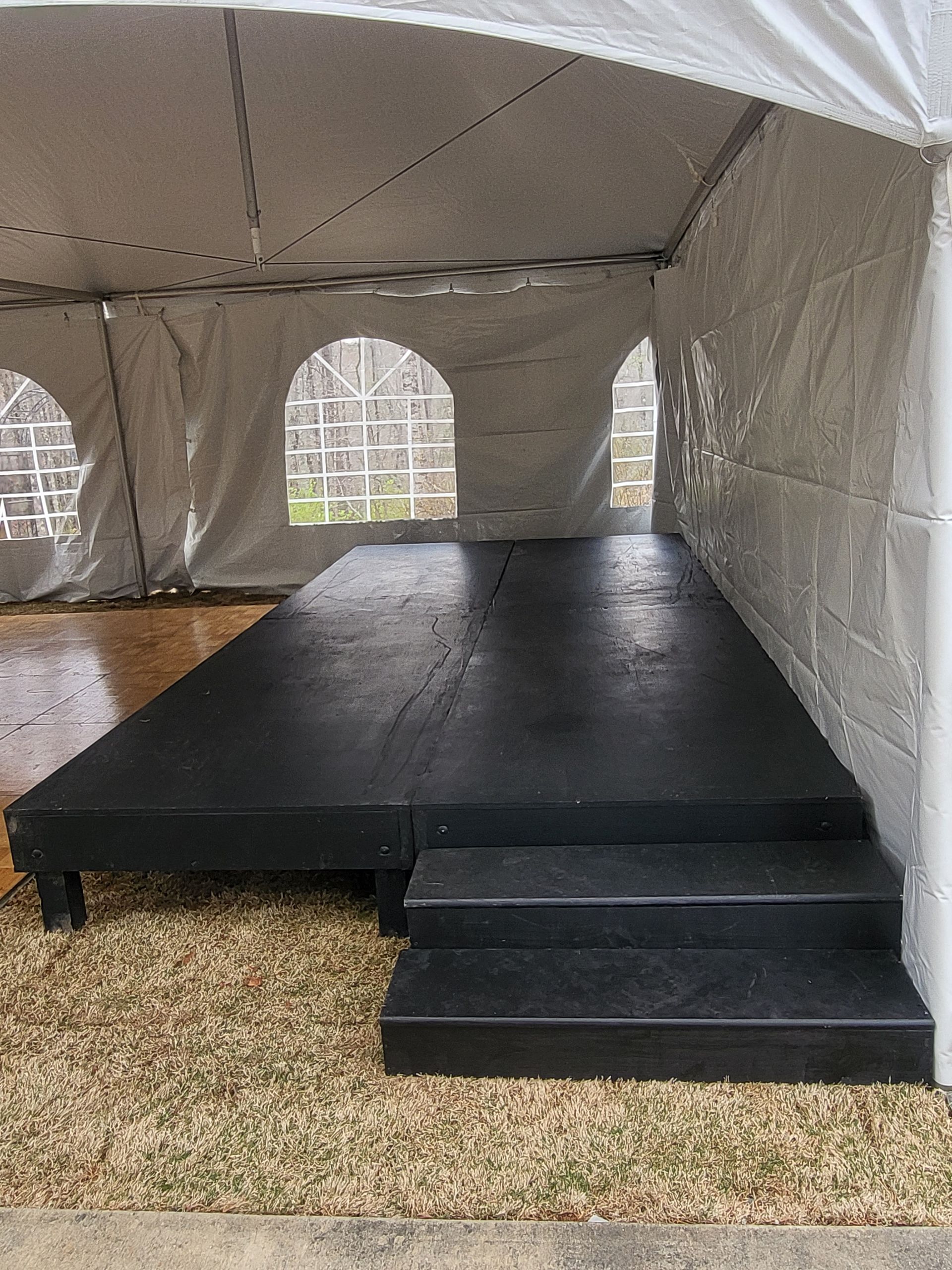 A white tent with a black stage inside of it.