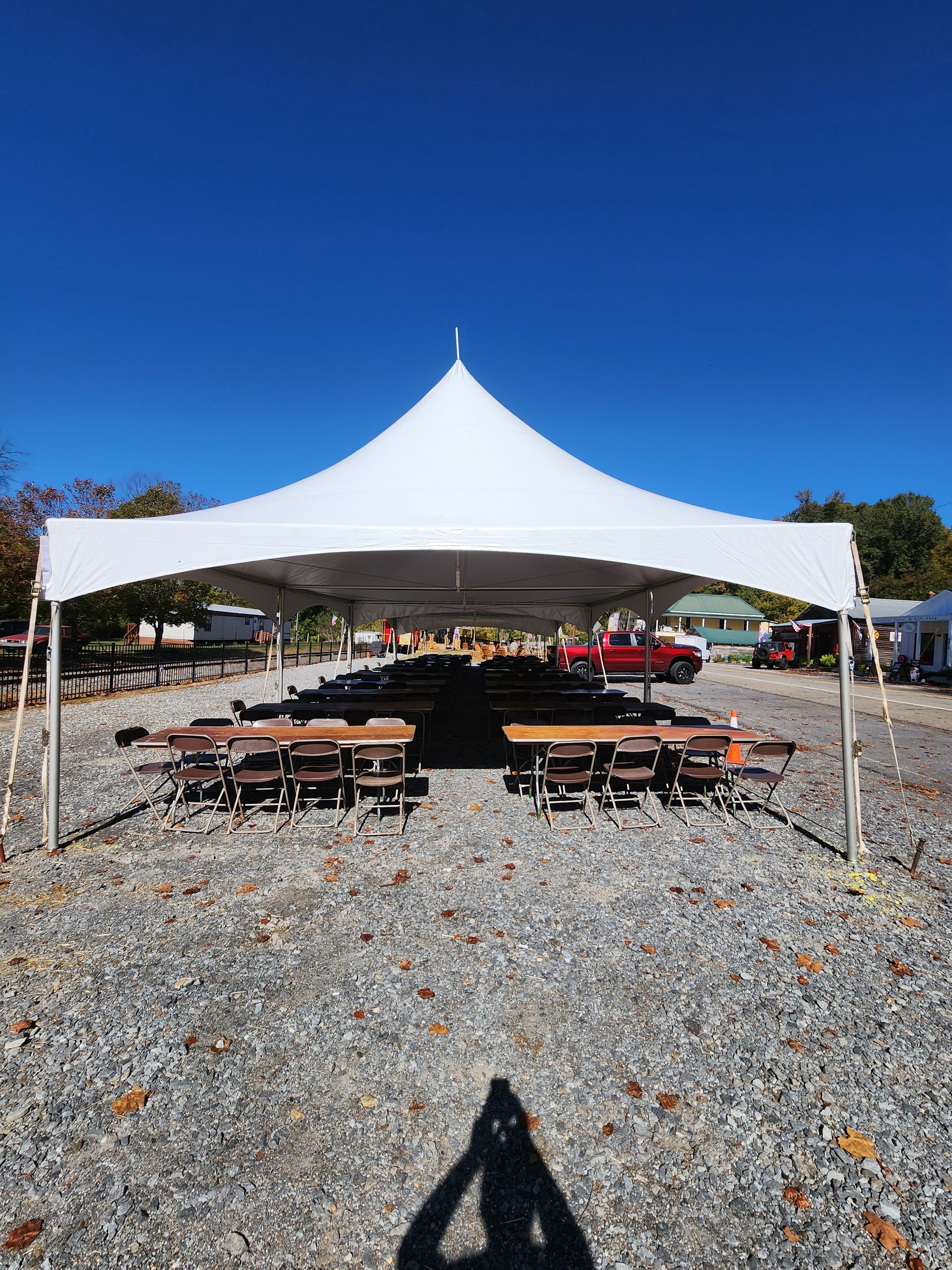 A white tent with tables and chairs underneath it in a gravel area.