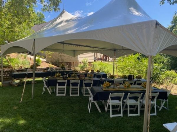 A white tent with tables and chairs underneath it.
