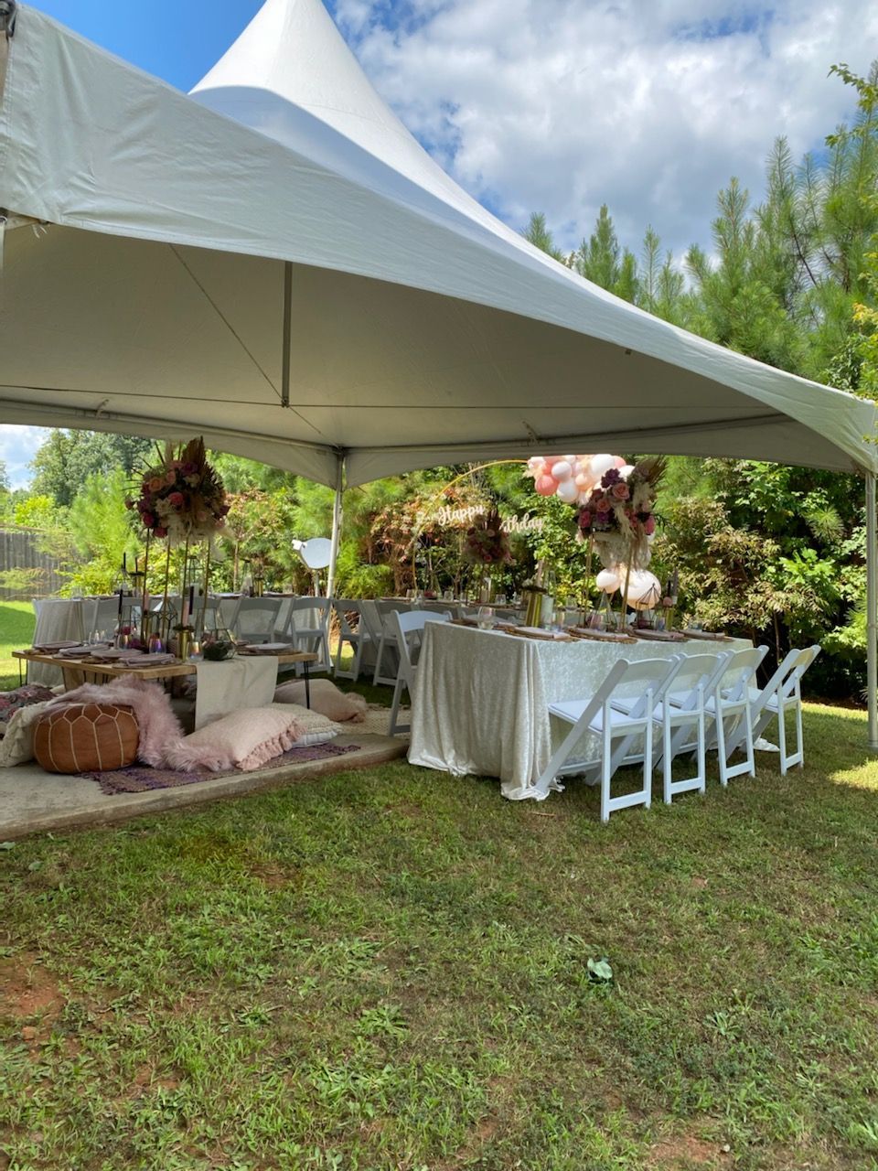 A white tent with tables and chairs underneath it in a field.