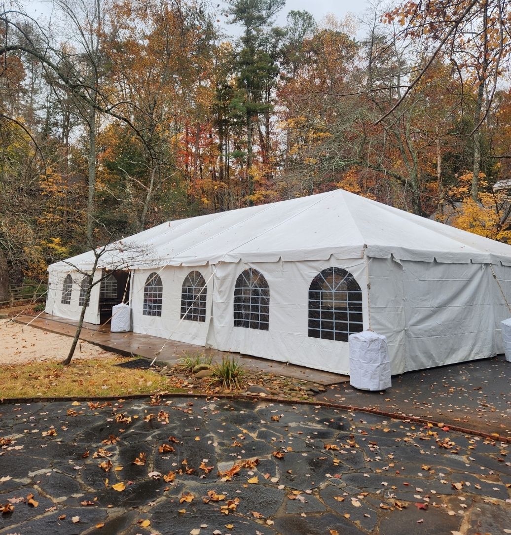 A large white tent is sitting in the middle of a forest.