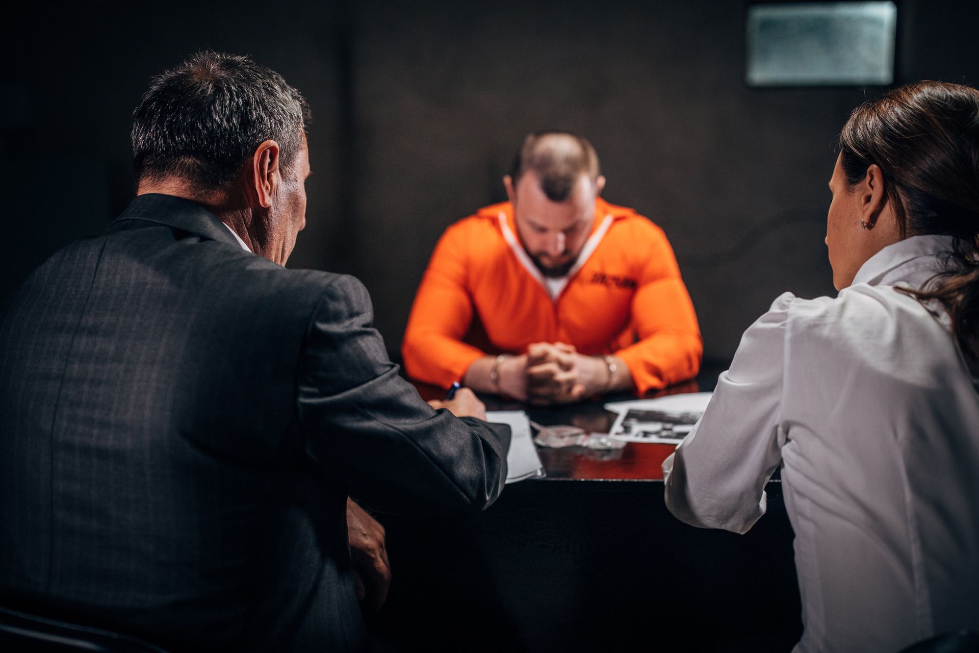 Man with handcuffs and two criminal defense lawyers sitting in the investigation room.