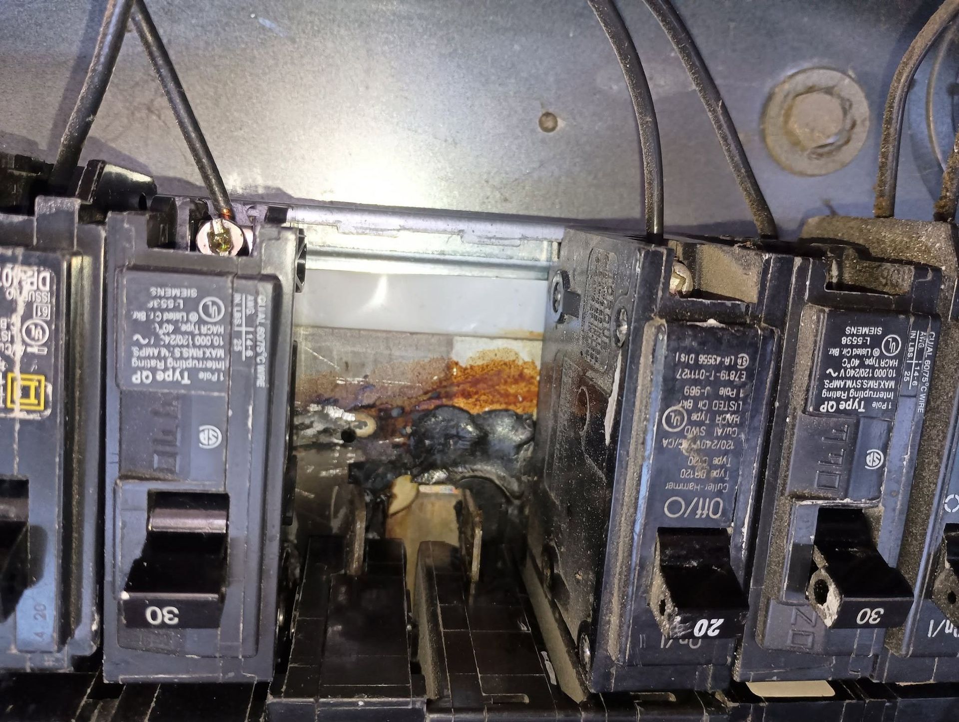 Inside an electrical panel with circuit breakers and wiring, showing open space in the center.