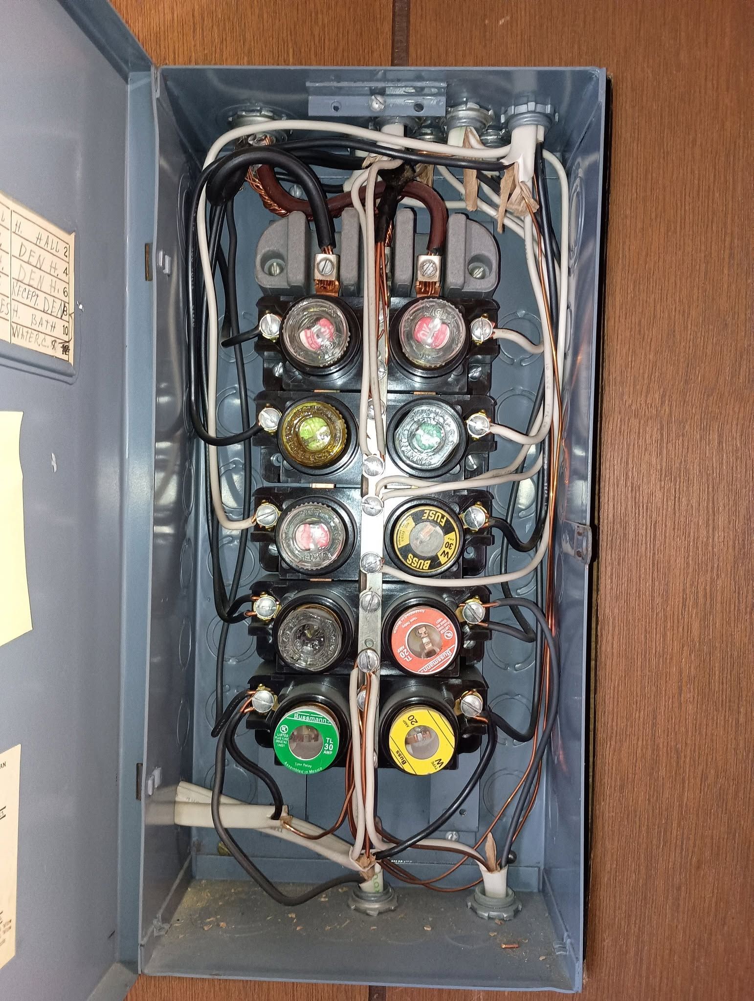 Open electrical panel with rows of colored circuit breakers and wiring inside a blue metal cabinet