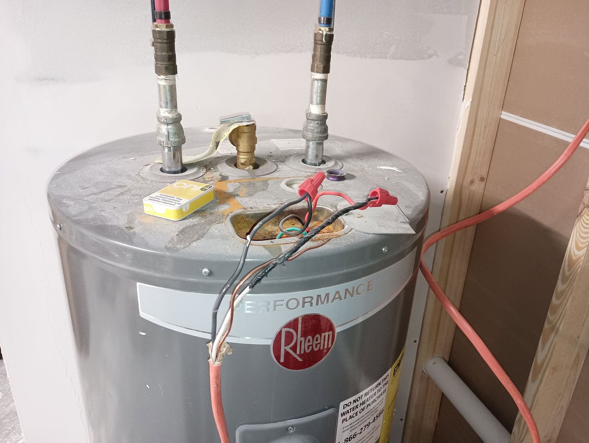 Gray water heater with pipes and hoses connected on top in a utility room