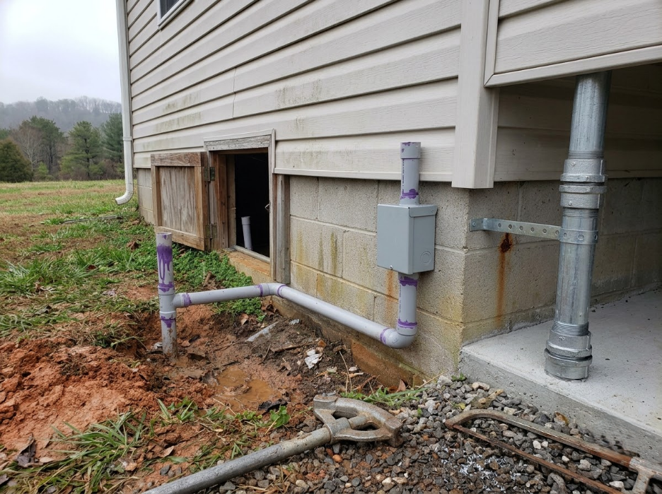 House exterior with exposed utility pipes and a small basement window near the foundation