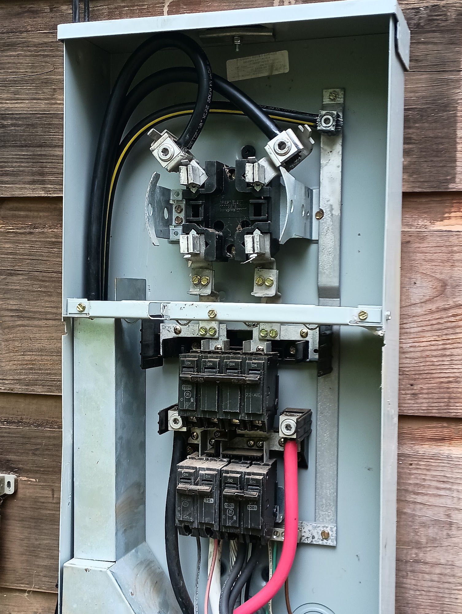 Open electrical service panel with wires and circuit breakers on a wall
