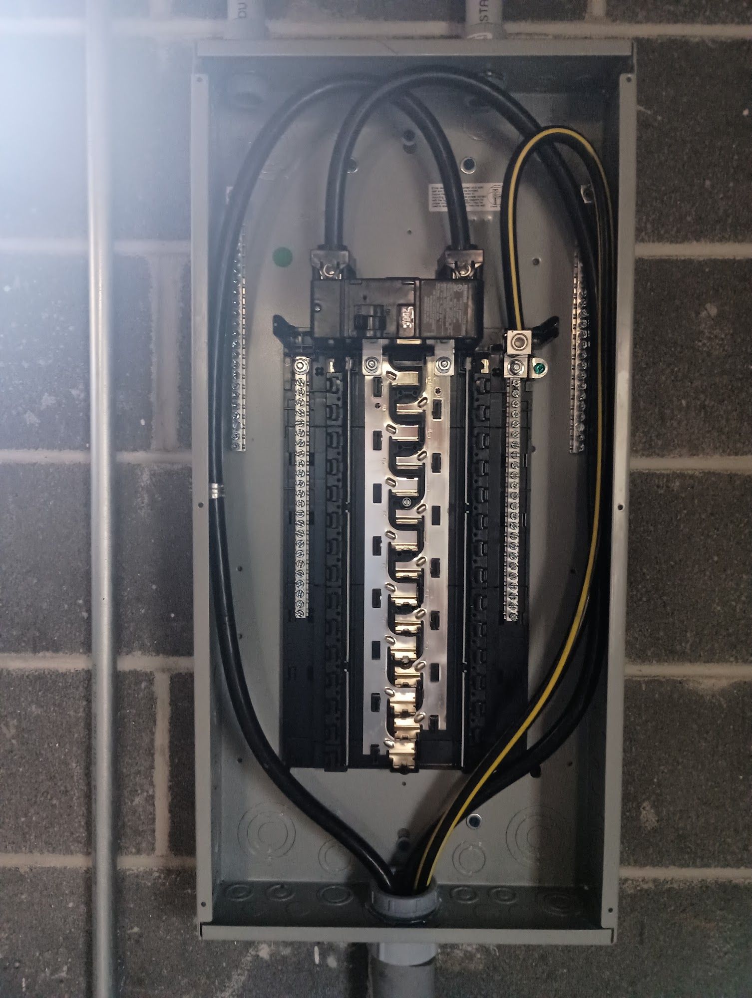 Electrical breaker panel with exposed wiring inside a wall box.