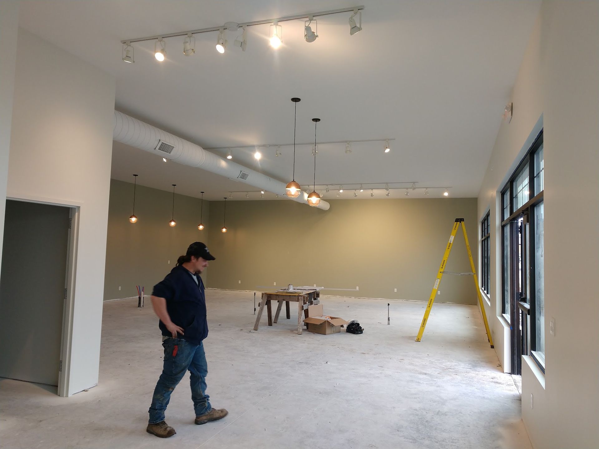 Unfinished room with tools, ladder, and one person standing near the left side
