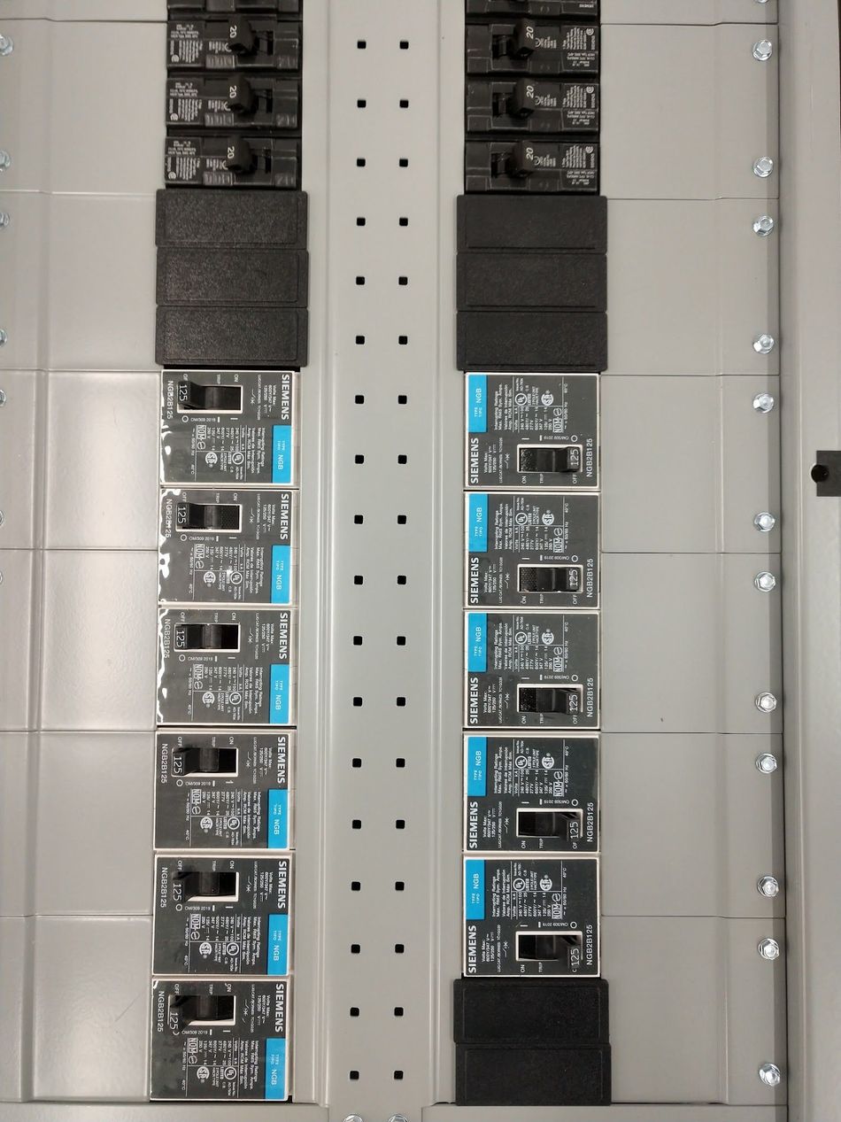 Electrical breaker panel with rows of blue-capped circuit breakers on a gray metal board.