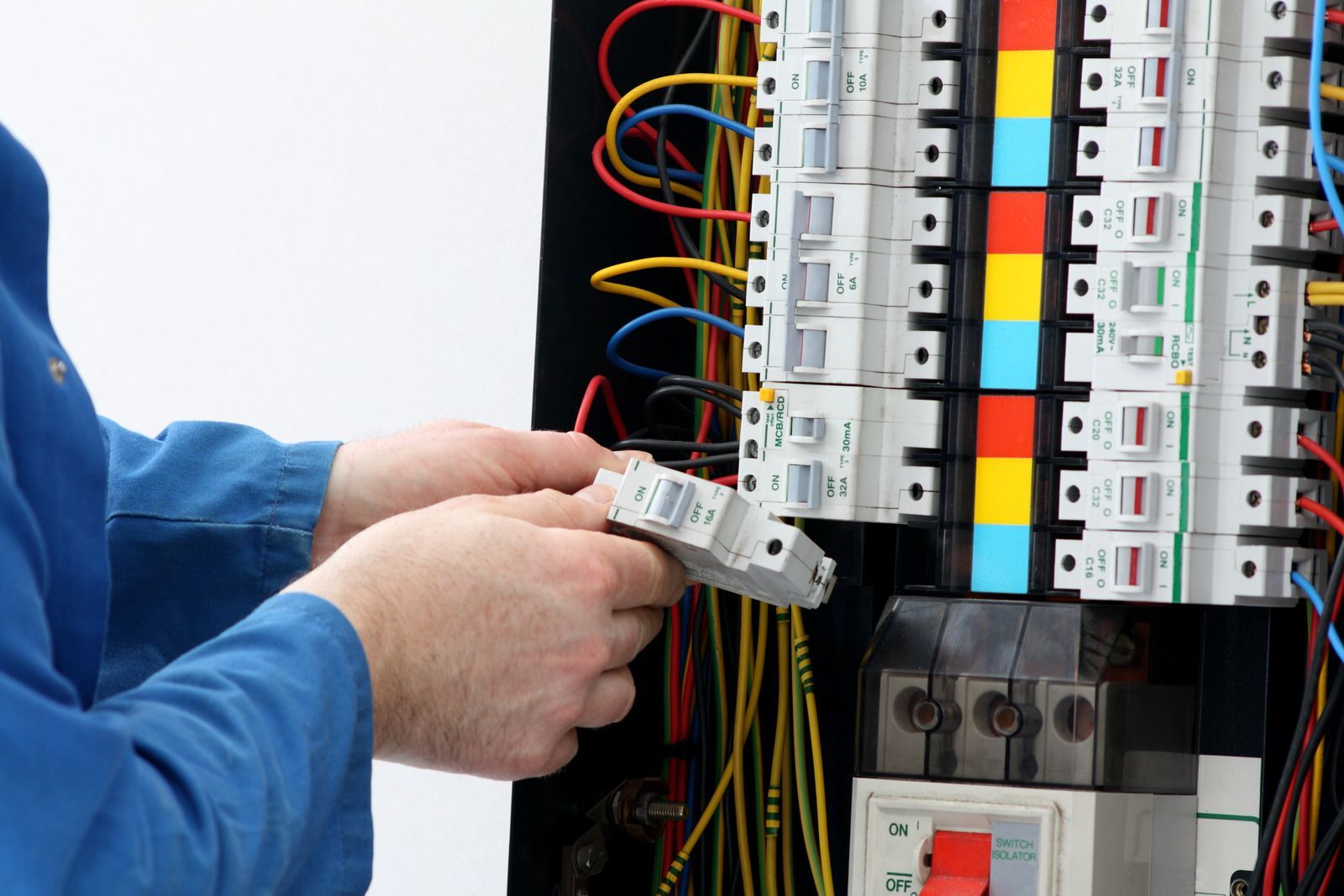 Electrician wiring a breaker panel with colored cables and circuit breakers visible