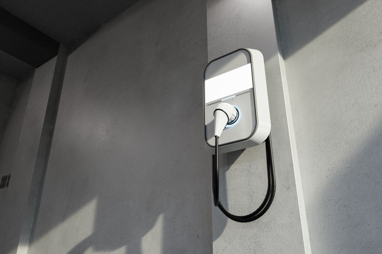 Wall-mounted EV charger with coiled cable on a gray exterior wall