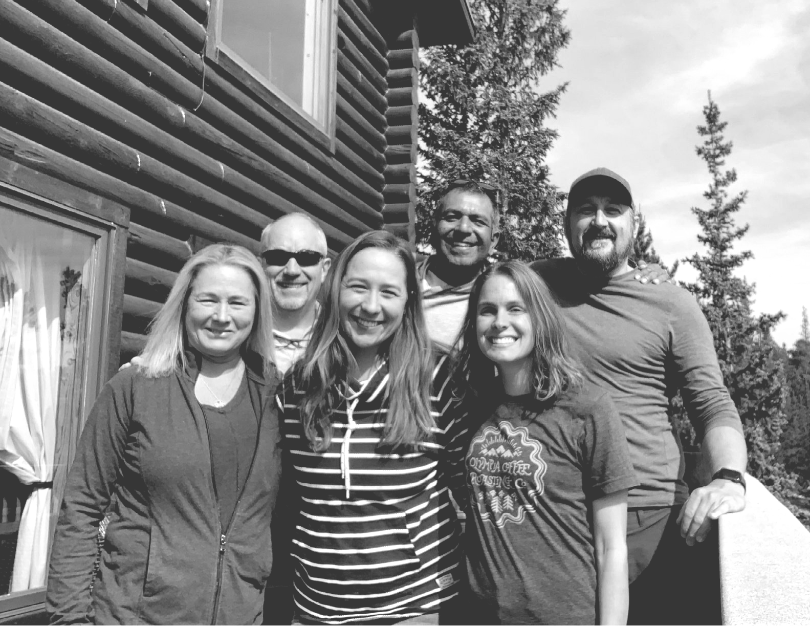 A group of people are posing for a picture in front of a log cabin.